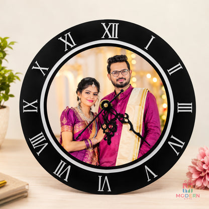 Personalized round black wall clock featuring a custom couple photo and Roman numeral design