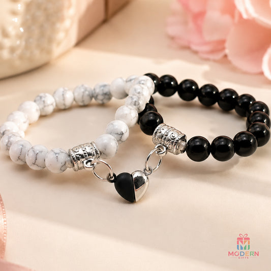 Matching couple bracelets with black and white beads and a connected heart design