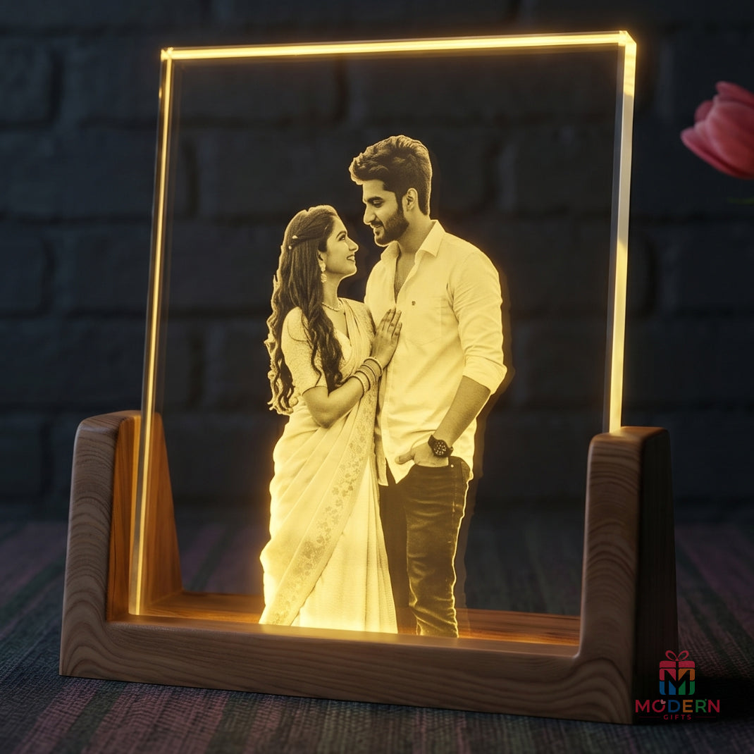 A personalized LED acrylic picture frame on a wooden stand, displaying a romantic couple portrait illuminated in warm yellow light against a dark brick wall background.